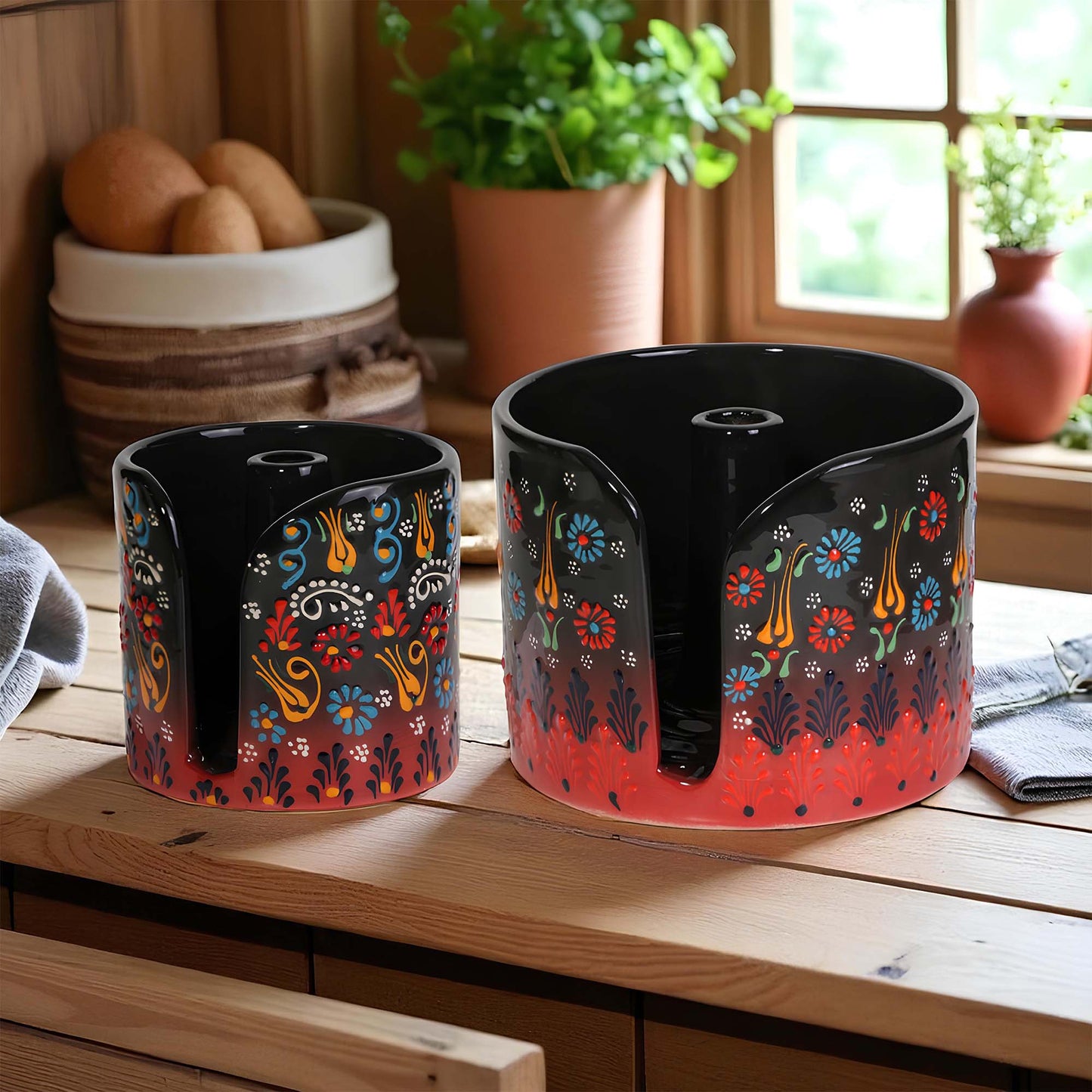 Two black paper towel holders with colorful floral patterns on a wooden surface.