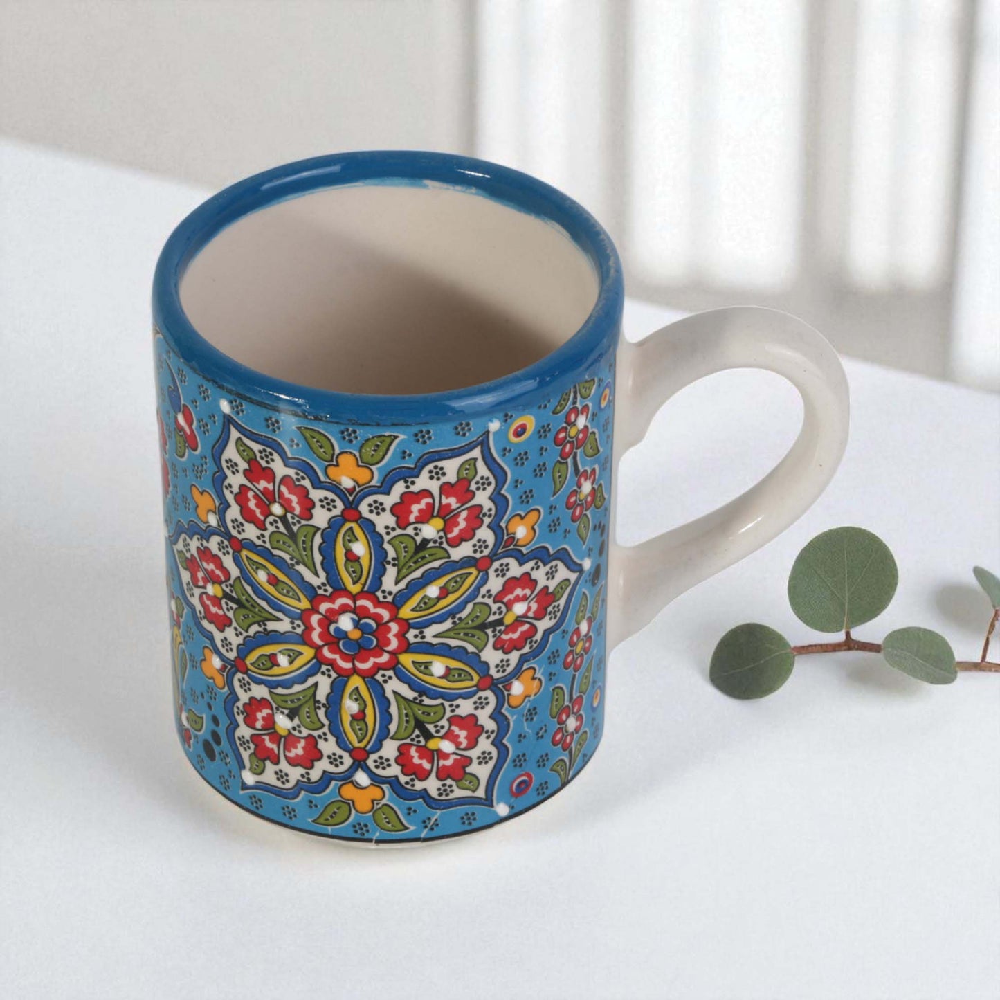 Ceramic coffee mug with colorful floral pattern on a white surface