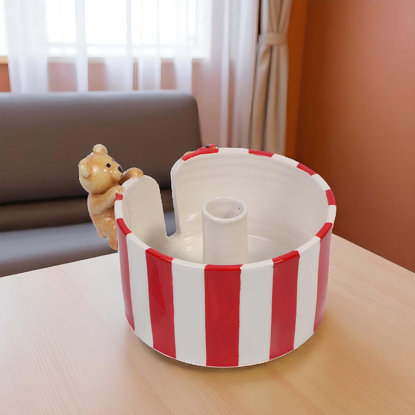 Red and white striped paper towel holder with a teddy bear on a wooden table