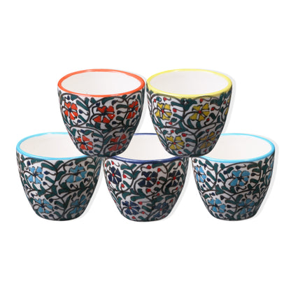 A set of five ceramic espresso cups with colorful floral patterns and blue rims.