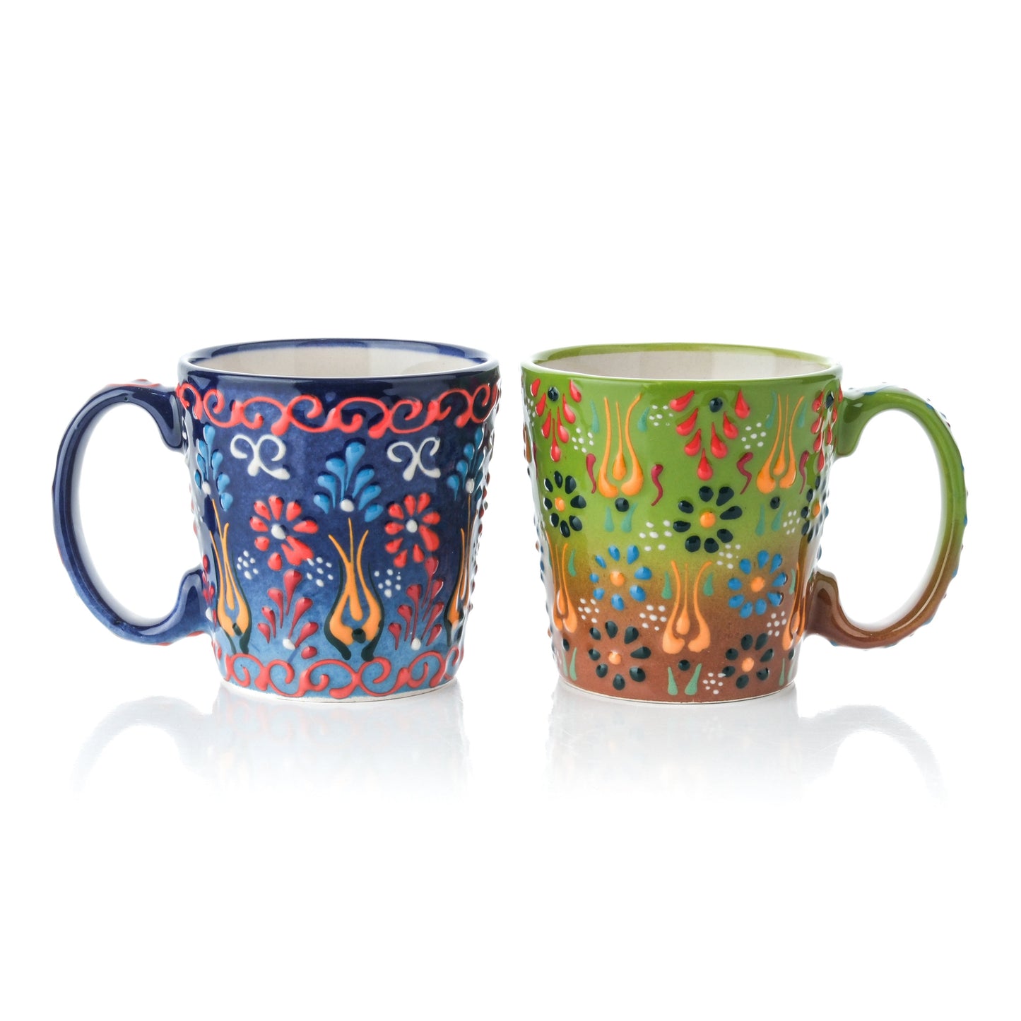 A set of two handcrafted ceramic mugs, one in navy and one in pistachio green color, both featuring a floral pattern and a tapered design.
