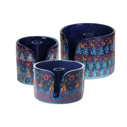 Three blue ceramic paper towel holders with colorful floral patterns on a white background