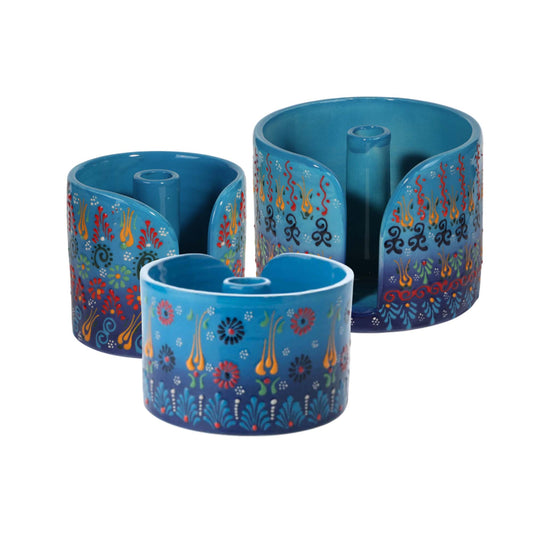 Set of three blue ceramic paper towel holders with colorful floral patterns on a white background