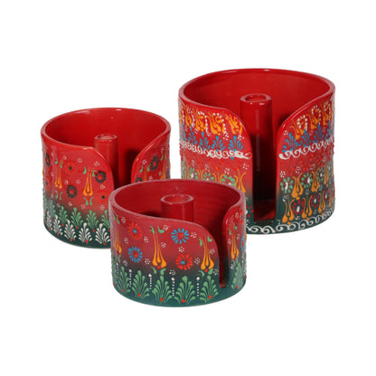 Three red cylindrical paper towel holders with colorful floral patterns on a white background