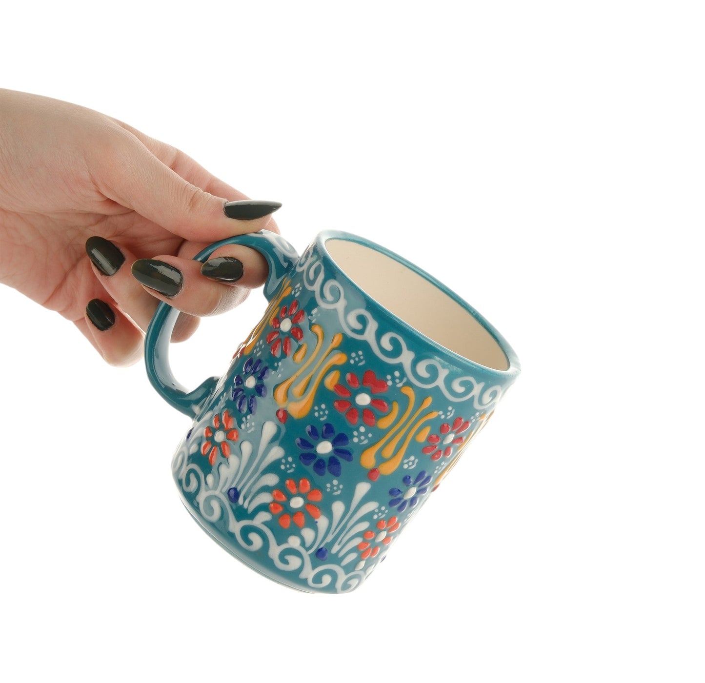A hand holding a colorful handcrafted ceramic mug with floral patterns.