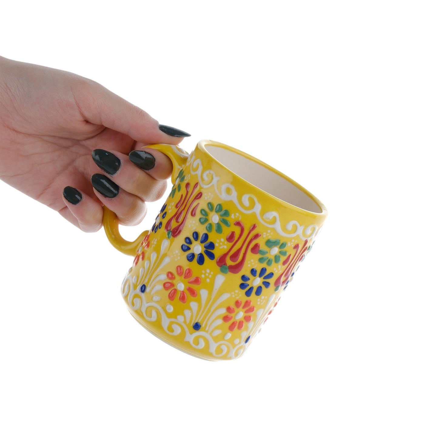 A hand holding a colorful handcrafted ceramic coffee mug with floral patterns.