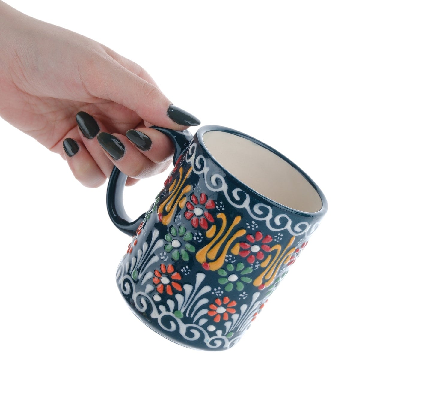 A hand holding a colorful handcrafted ceramic coffee mug with floral patterns.
