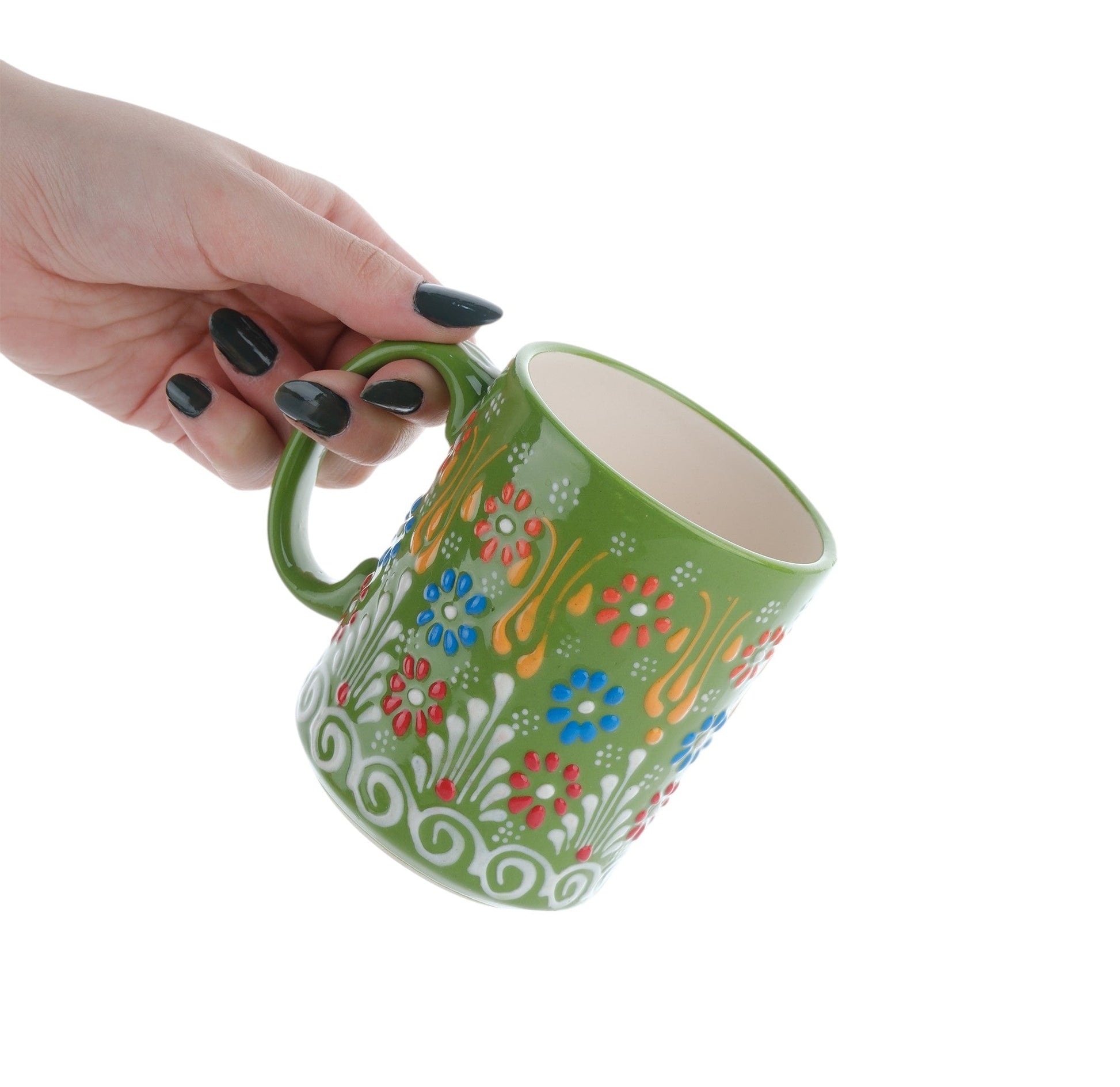 A hand holding a colorful handcrafted ceramic coffee mug with floral patterns.