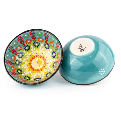 Two ceramic bowls, one with a colorful floral design and the other plain blue, on a white background.