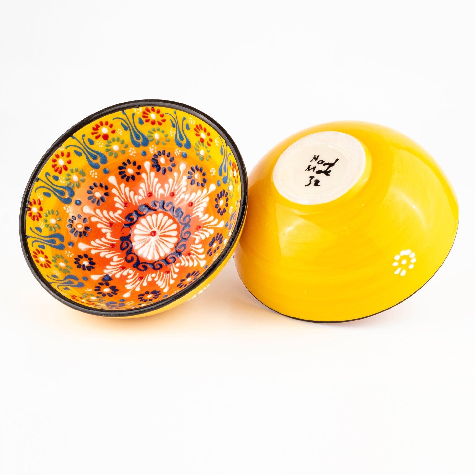Two ceramic bowls, one with floral design and the other plain yellow, on a white background.