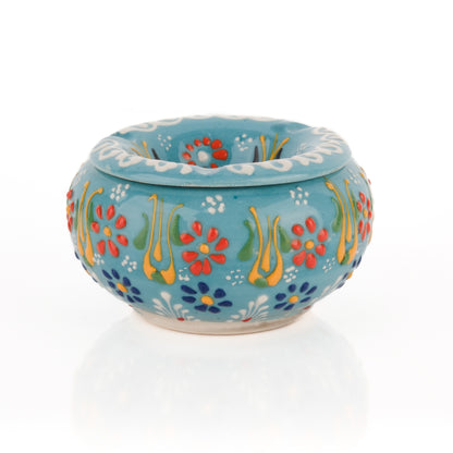 A handmade ceramic ashtray with a floral pattern in turquoise color, featuring a lid.