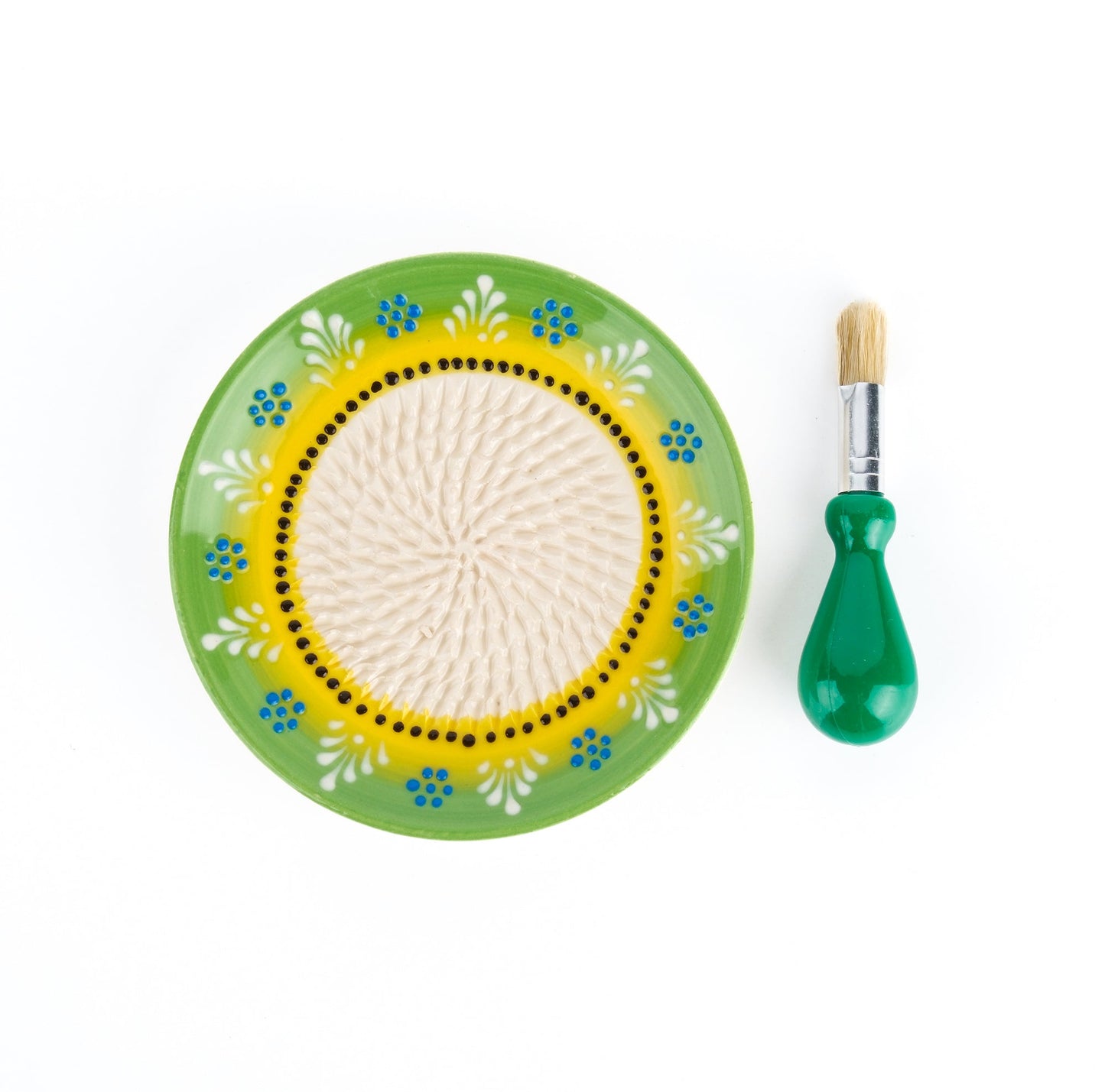 Decorative  ceramic garlic grater plate with floral patterns and a brush on a white background