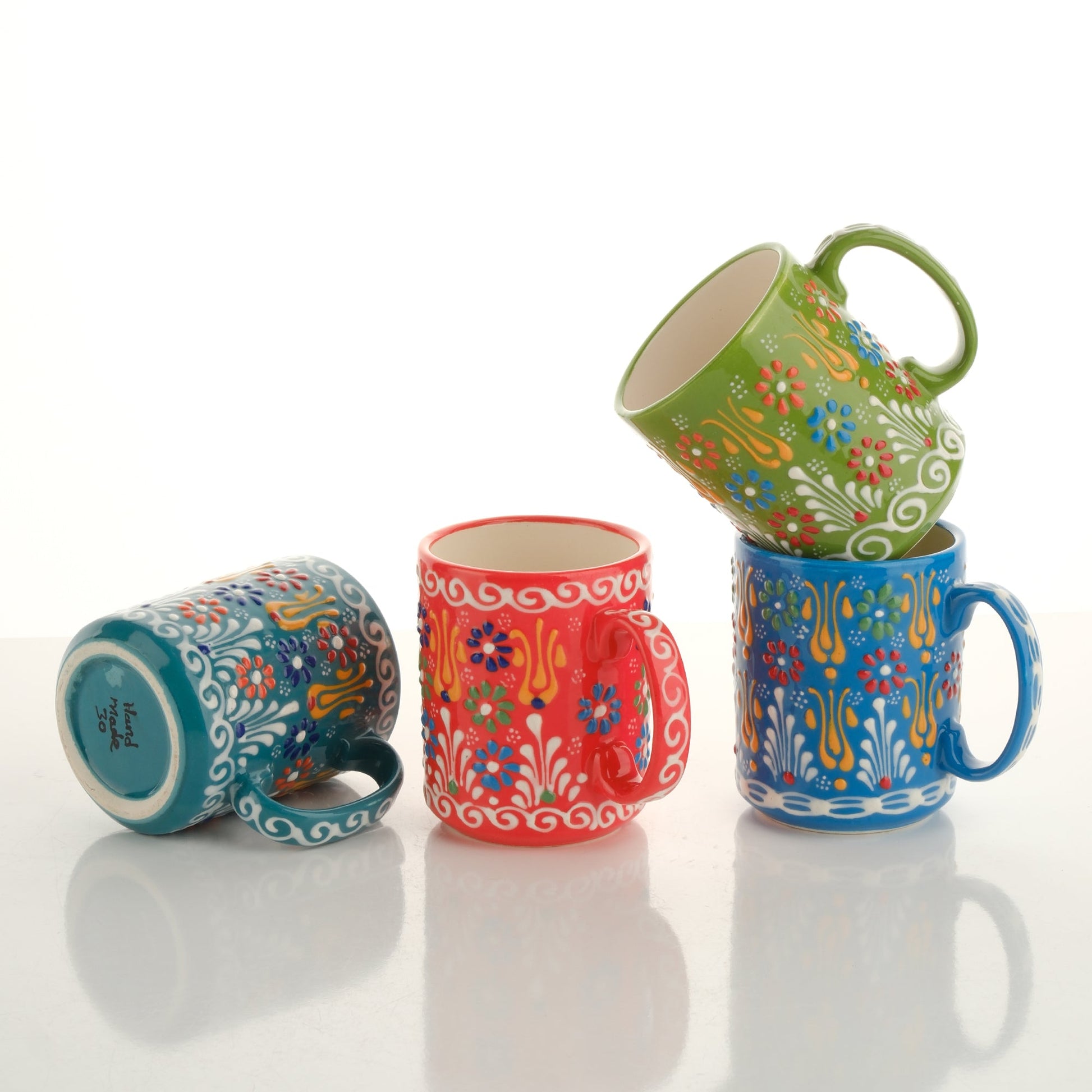 A set of colorful handcrafted ceramic mugs with floral and geometric patterns, displayed in a stacked arrangement.