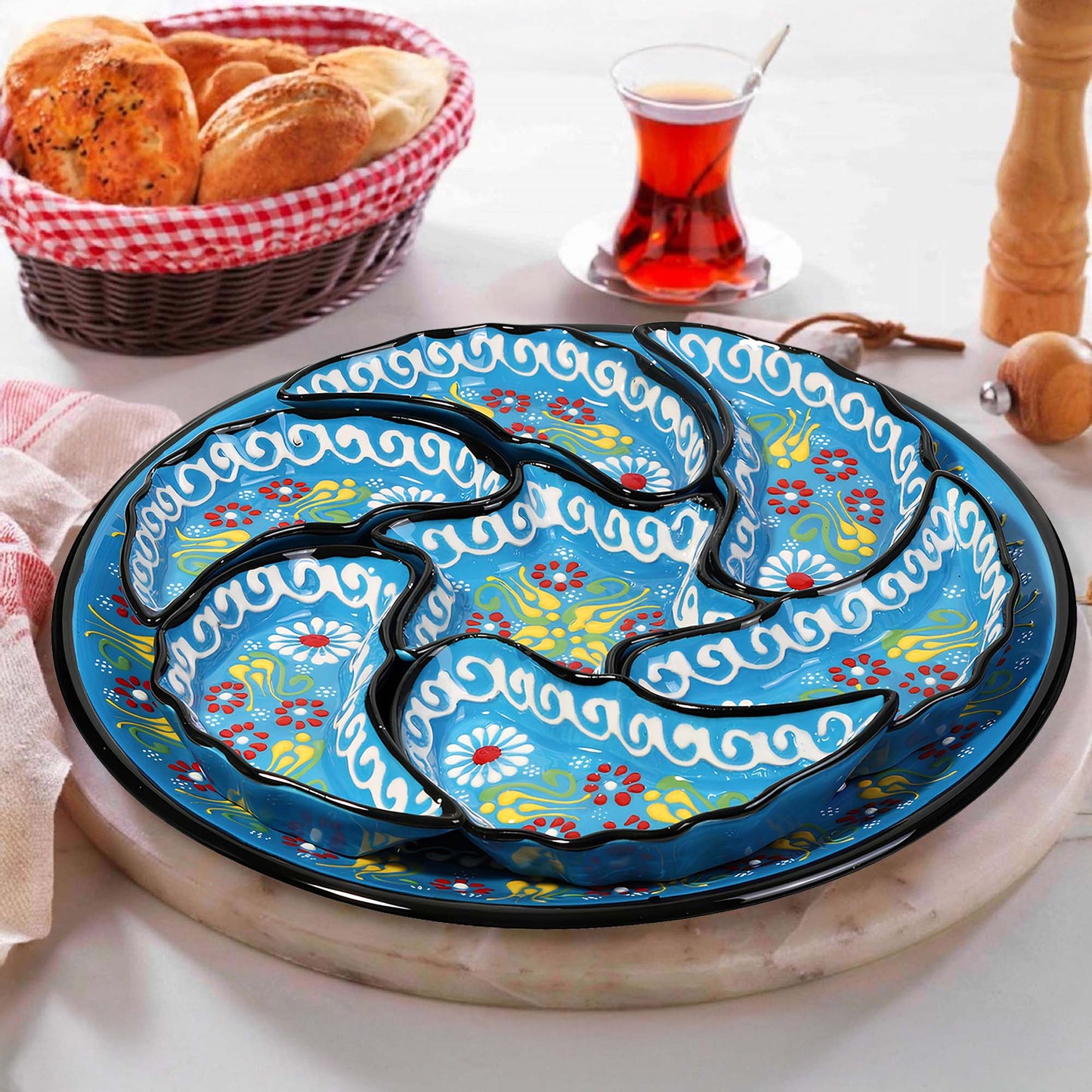 Decorative ceramic snack serving tray set with floral patterns on a table with bread and tea.