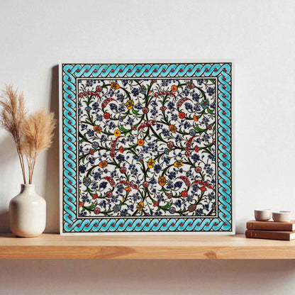 Decorative ceramic tile wall art with floral pattern on a wooden shelf