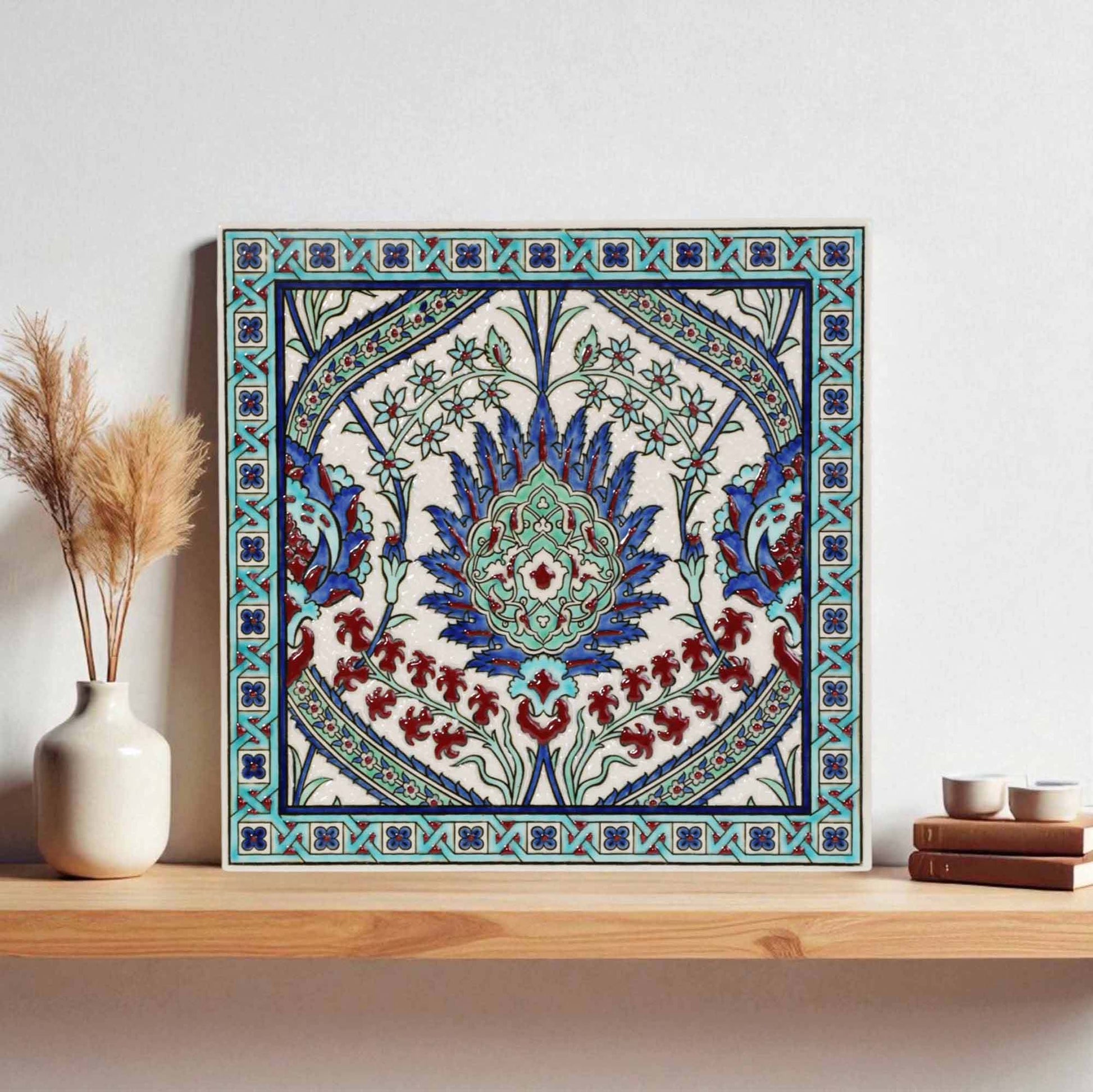 Decorative ceramic tile with intricate patterns on a wooden shelf against a light wall.