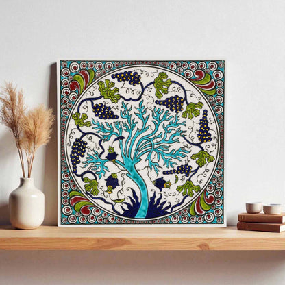 Decorative ceramic tile wall art with a tree design on a wooden shelf.