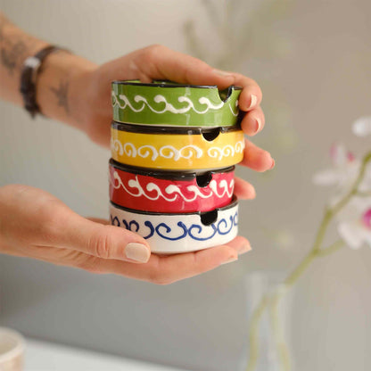 Stack of colorful ceramic ashtrays held by a hand with a blurred background