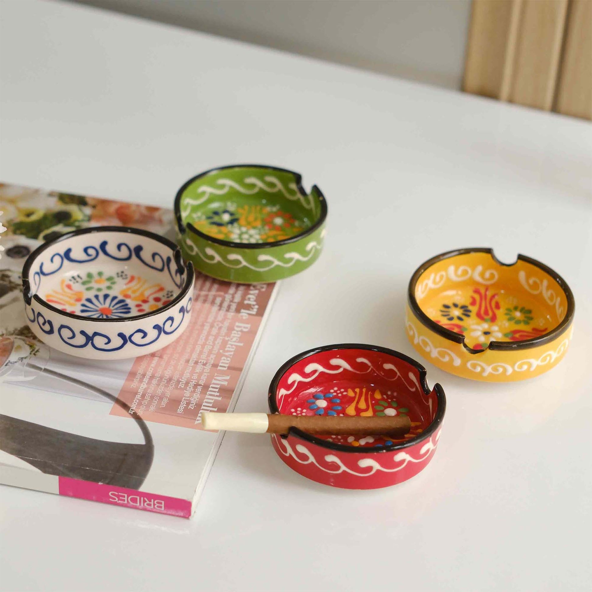 Set of colorful ceramic ashtrays on a magazine with a white background