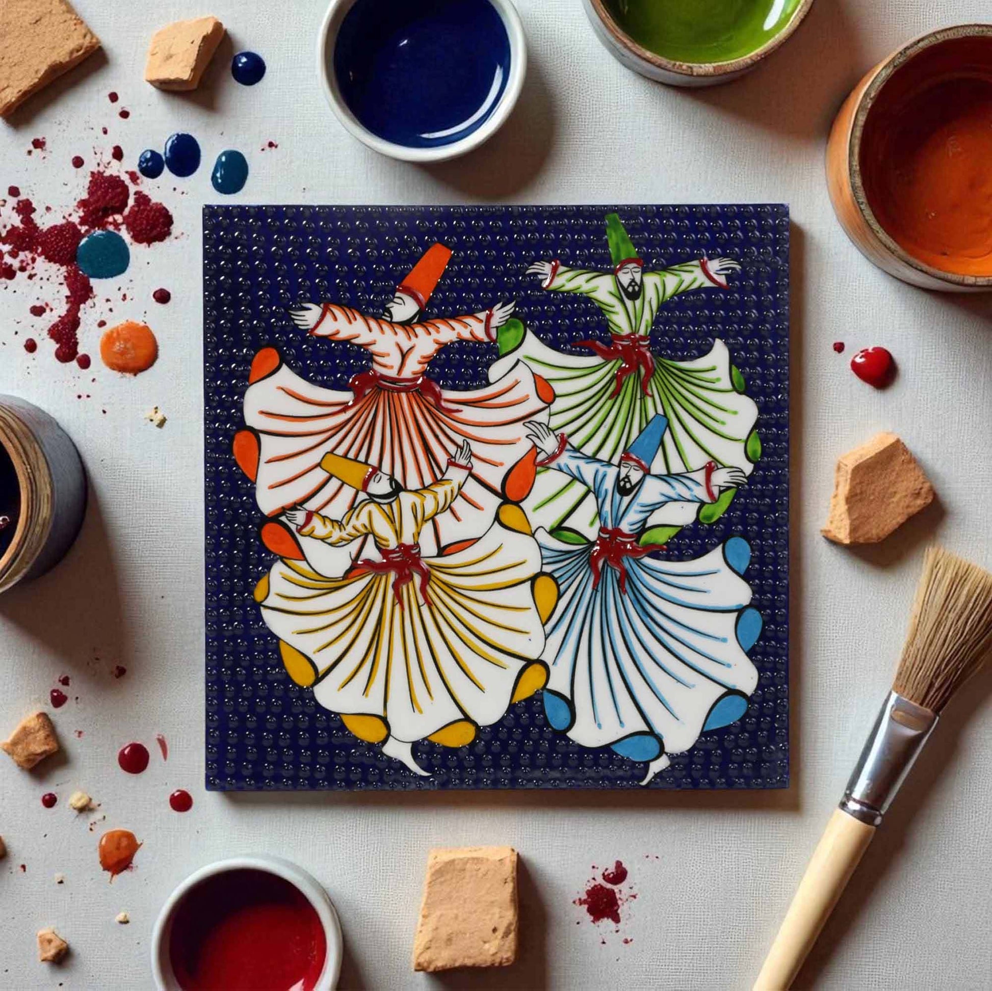 Colorful ceramic tile with dancer design surrounded by painting supplies on a white surface
