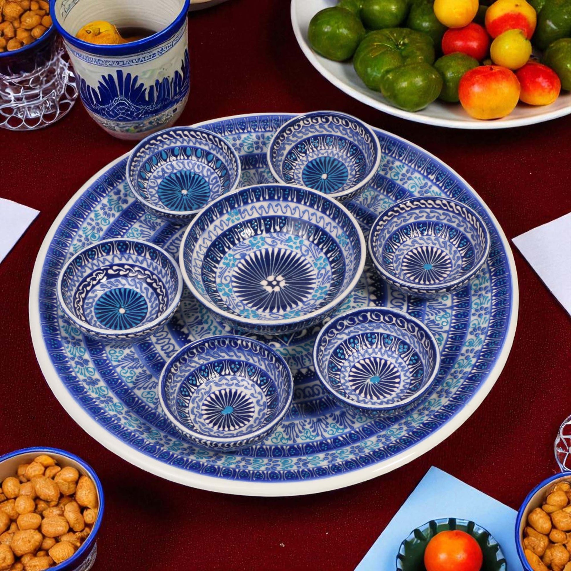 Set of blue and white ceramic dishes on a table with snacks and fruits.