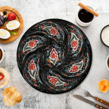 Set of decorative black plates with floral patterns on a light gray surface with food items.