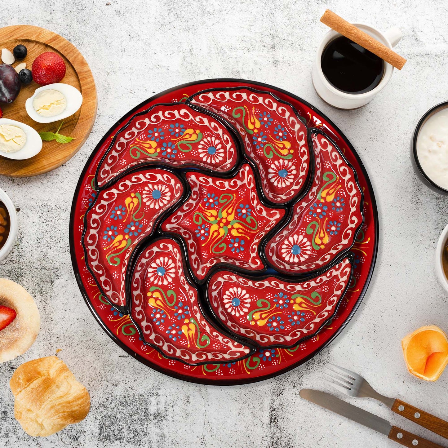 Decorative red snack serving tray set with intricate patterns on a table with food and coffee.
