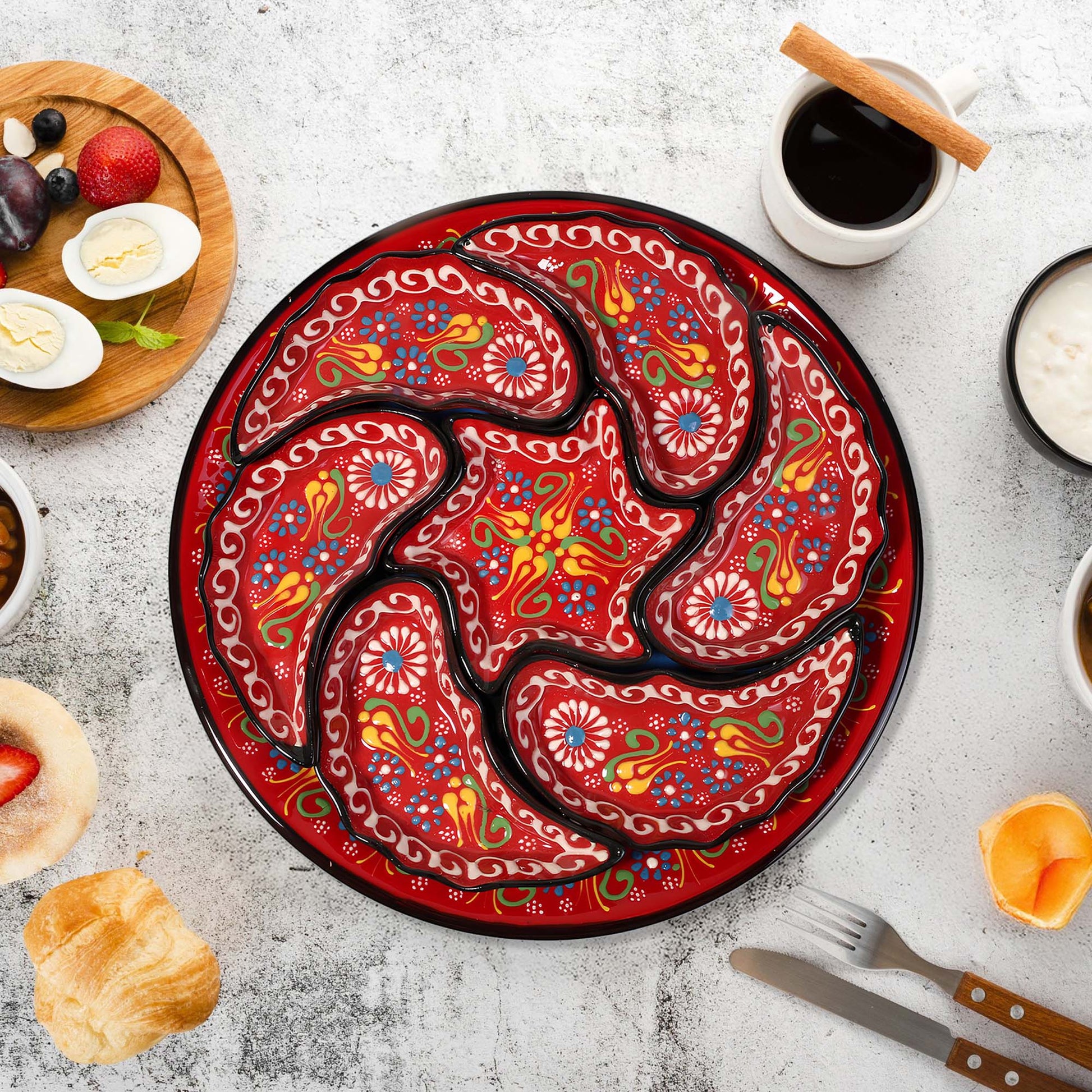 Decorative red snack serving tray set with intricate patterns on a table with food and coffee.