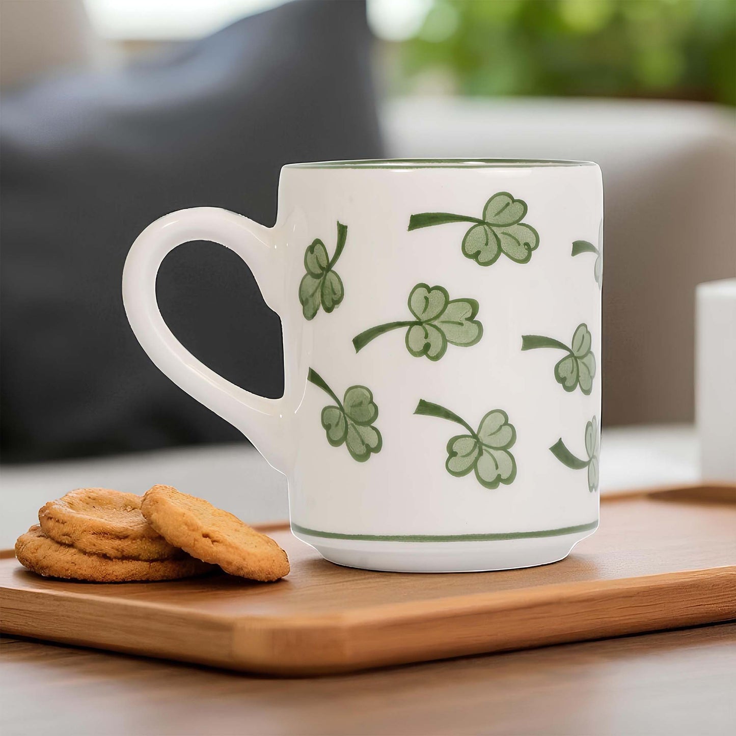 White coffee mug with green clover patterns on a wooden tray with cookies