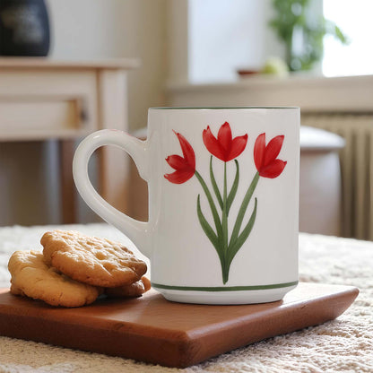 White coffee mug with red tulip design on a wooden tray with cookies