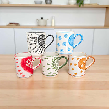 Set of colorful mugs with various designs on a wooden surface.