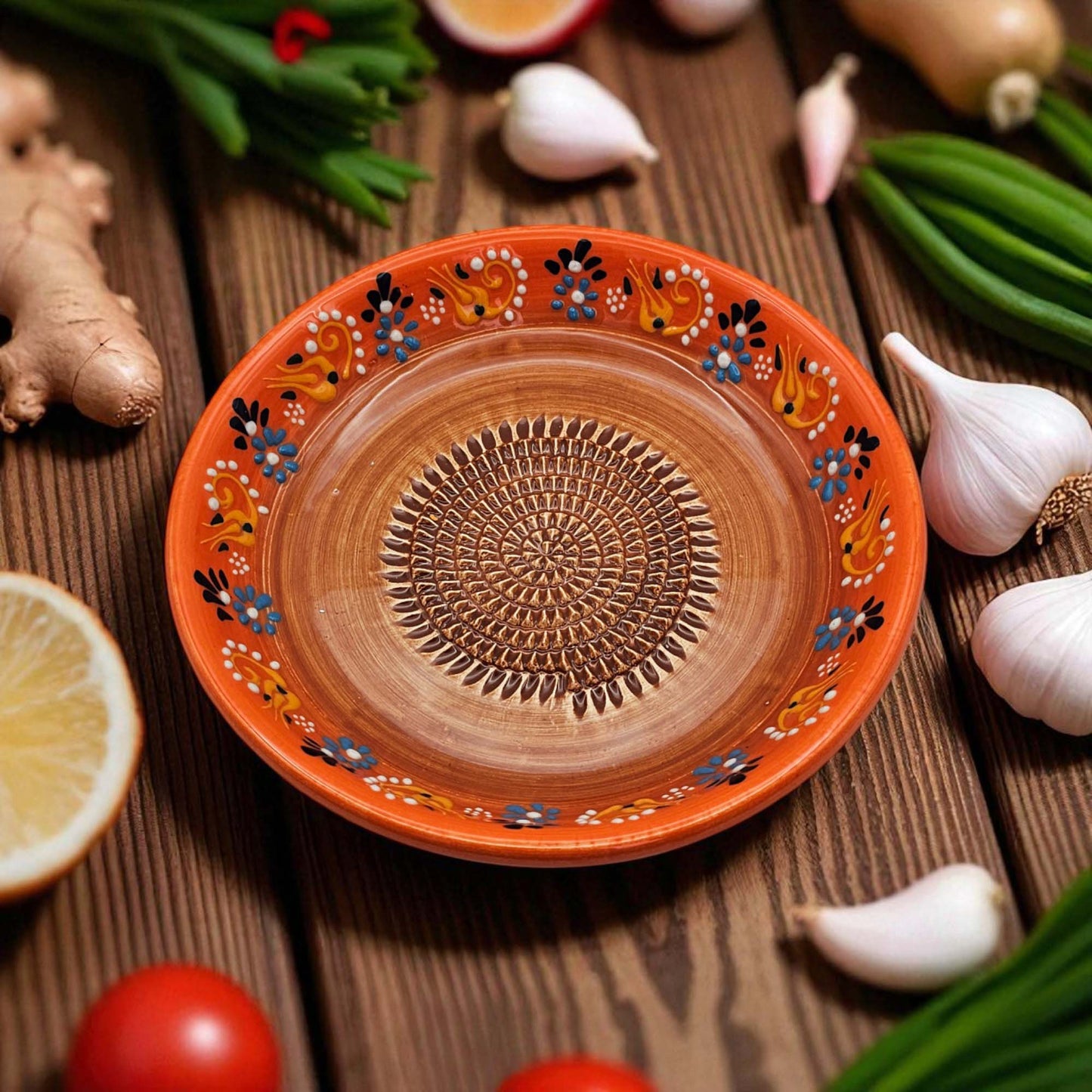 Decorative ceramic garlic grater bowl with intricate patterns on a wooden surface with fresh ingredients.