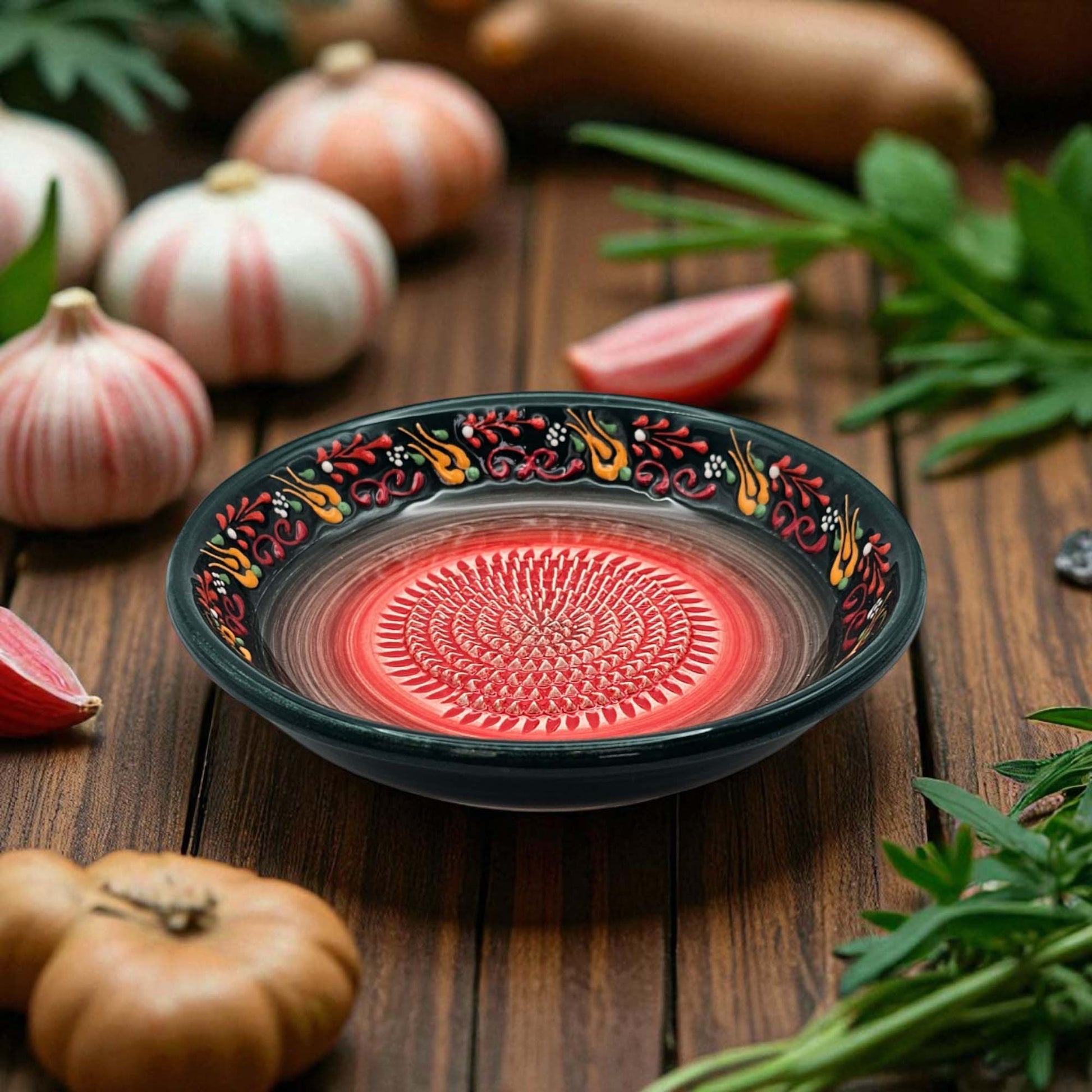 Decorative garlic grater bowl with a red interior on a wooden surface with pumpkins and herbs.