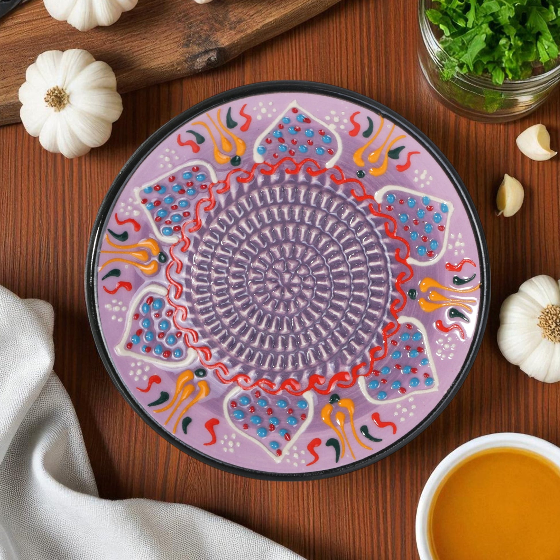 Decorative ceramic garlic grater with colorful patterns on a wooden table with pumpkins and a bowl of soup.