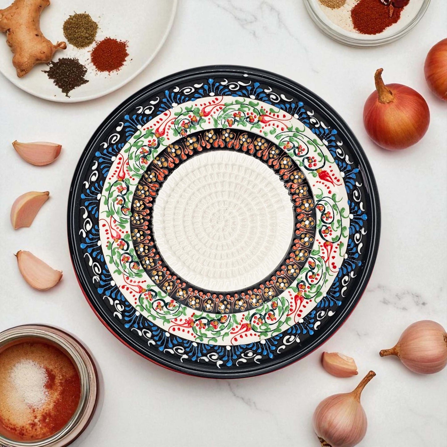 Decorative ceramic garlic grater bowl with intricate patterns on a white surface with ingredients.