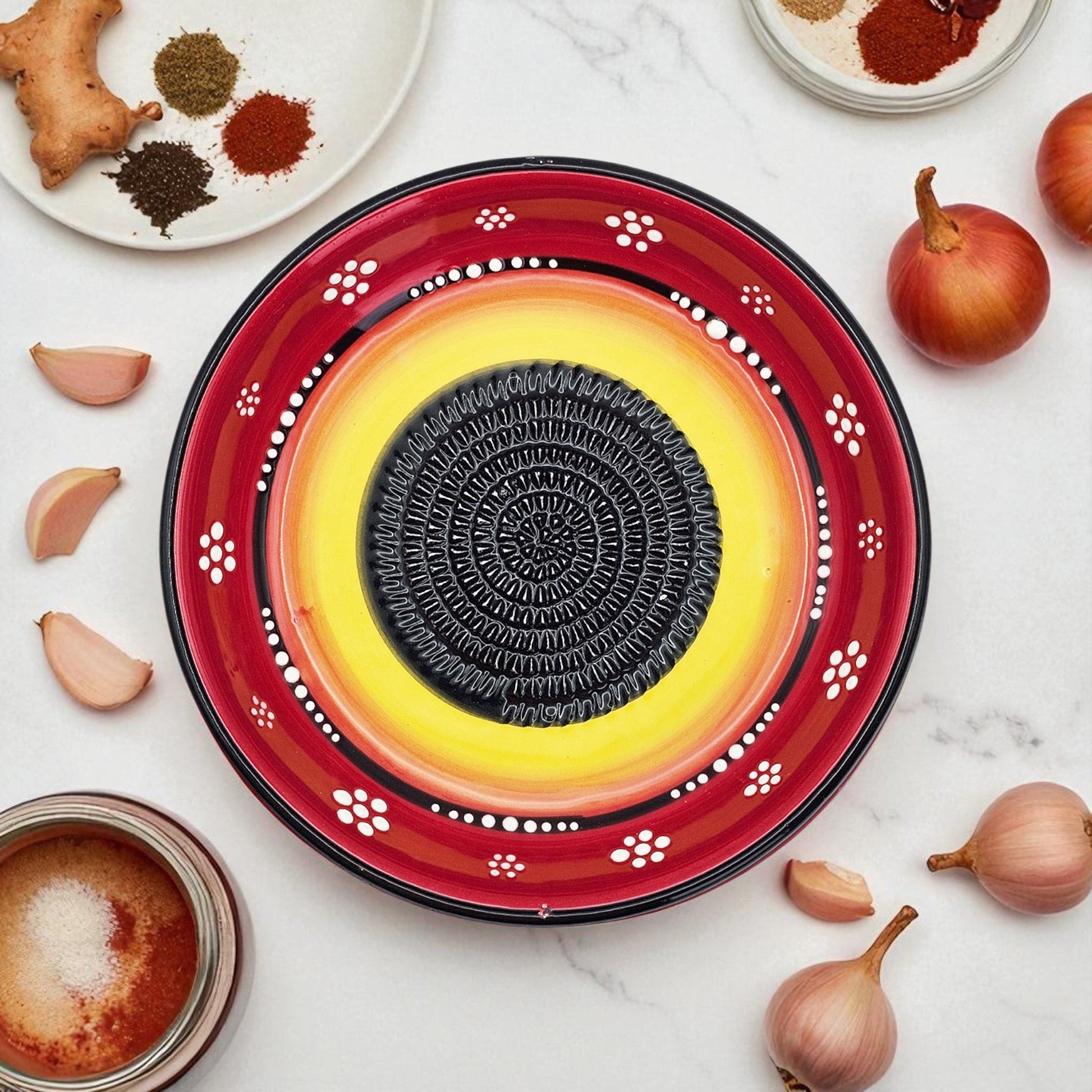 Decorative garlic grater bowl with a central circular design on a white surface with ingredients.