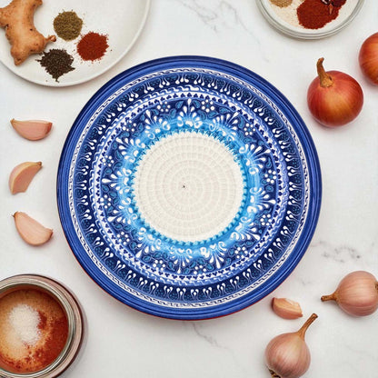 Blue decorative garlic grater bowl with white center on a marble surface with ingredients.