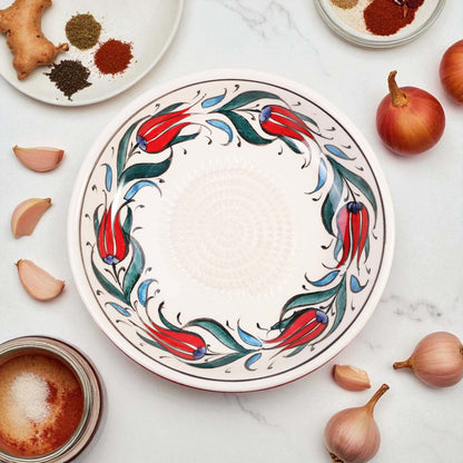 Decorative ceramic garlic grater bowl with floral design on a marble surface with ingredients.