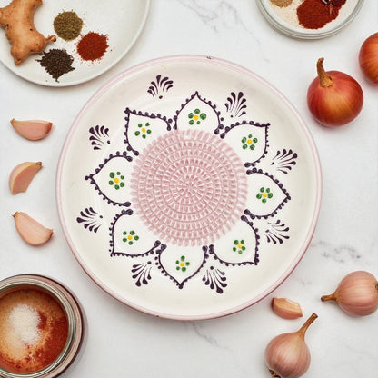 Decorative ceramic garlic grater bowl with intricate patterns on a marble surface with ingredients.