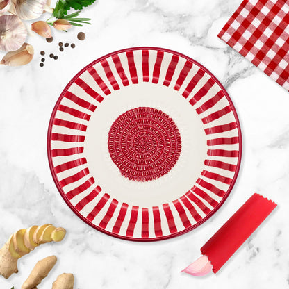 Red and white striped garlic grater bowl on a marble surface with ginger and a checkered cloth.