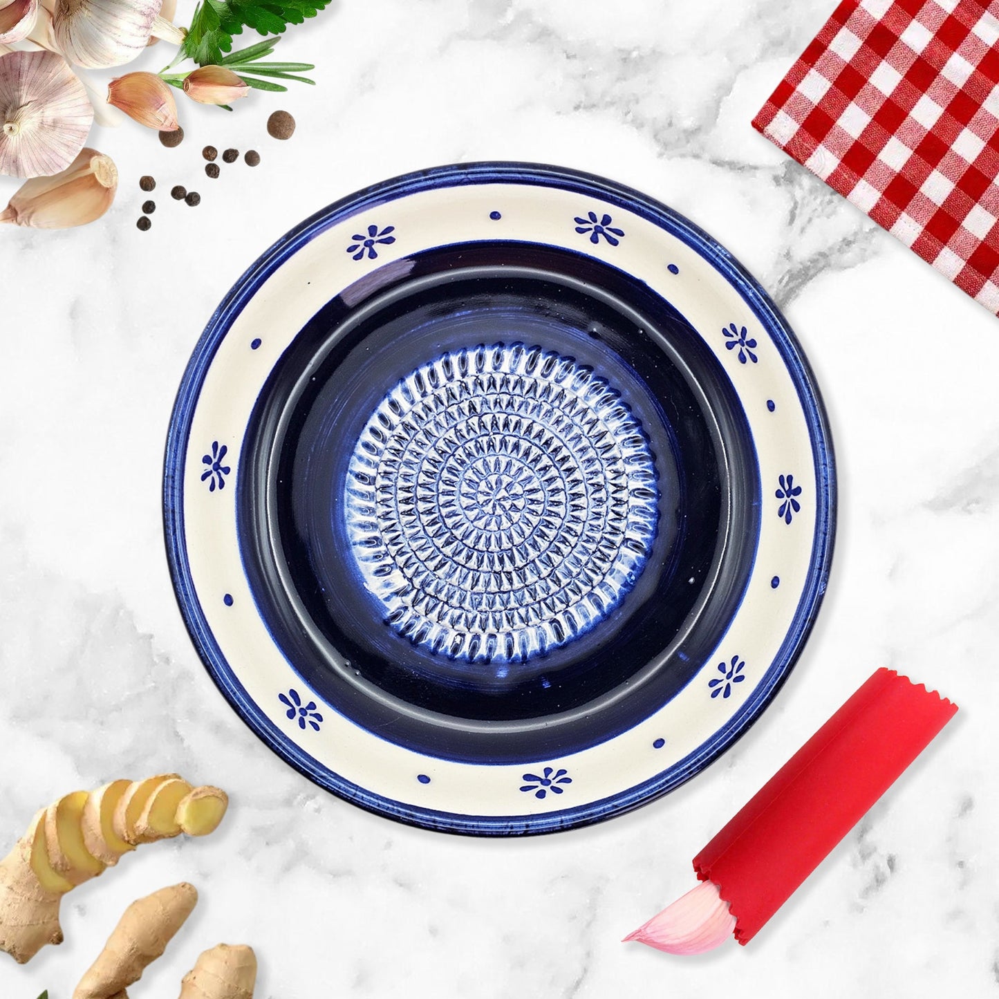 Decorative blue ceramic garlic grater bowl with floral patterns on a marble surface with kitchen items.