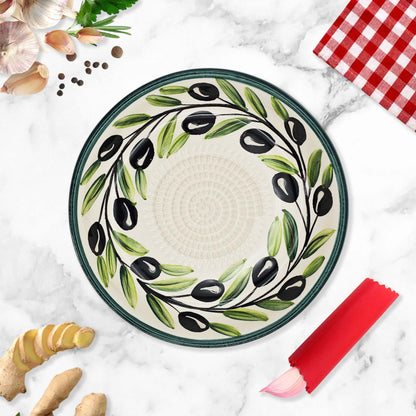 Decorative garlic grater bowl with olive design on a marble surface with kitchen items.