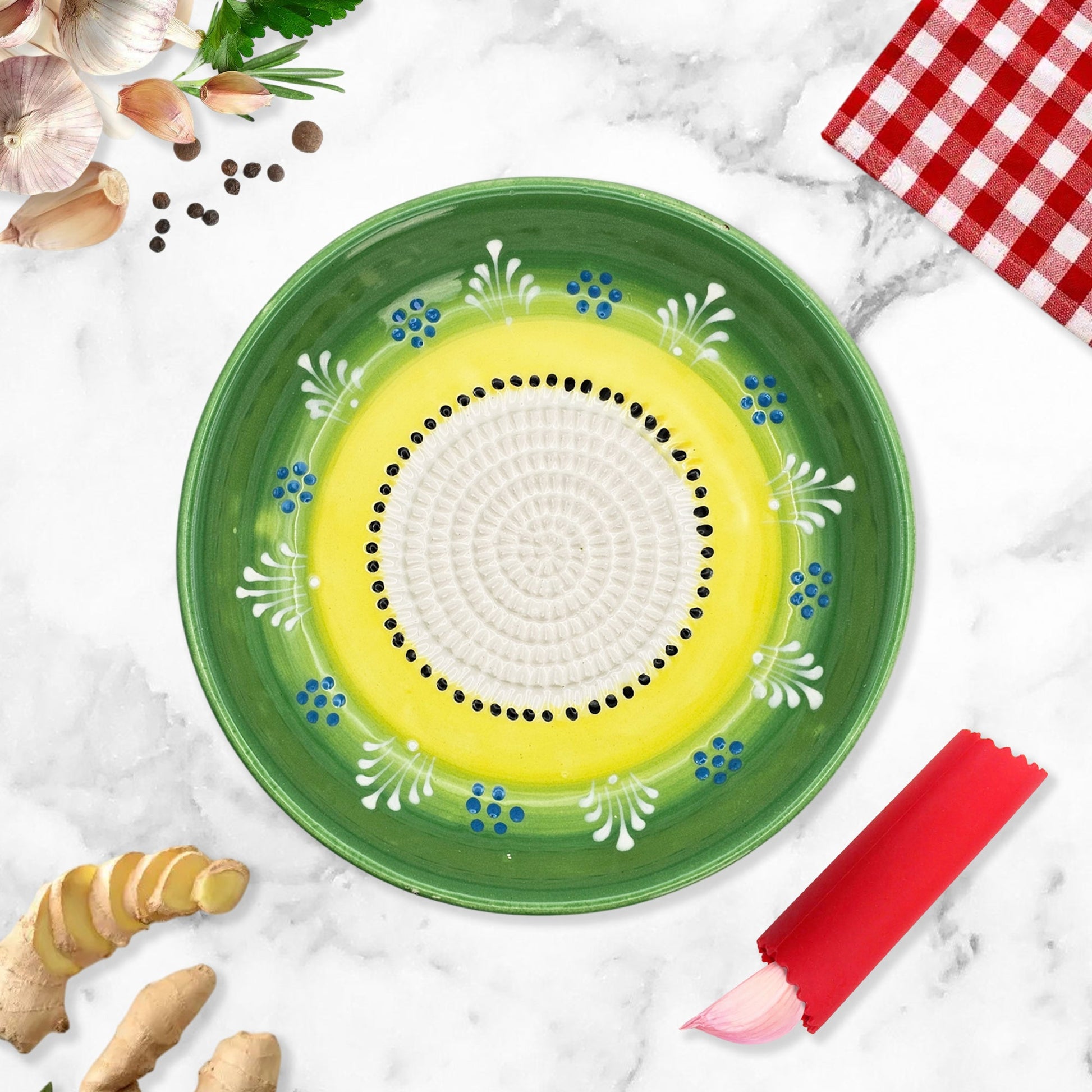 Decorative garlic grater bowl with floral patterns on a marble surface with kitchen items.