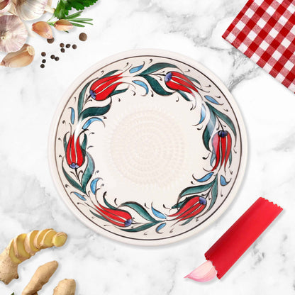 Decorative ceramic garlic grater bowl with floral design on a marble surface with kitchen items.