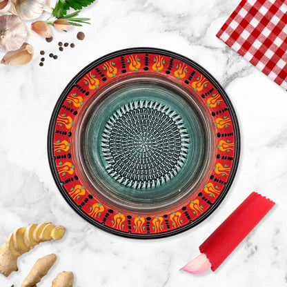 Decorative ceramic garlic grater bowl with colorful on a marble surface with kitchen items.