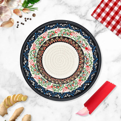 Decorative garlic grater bowl with floral patterns on a marble surface with kitchen items.