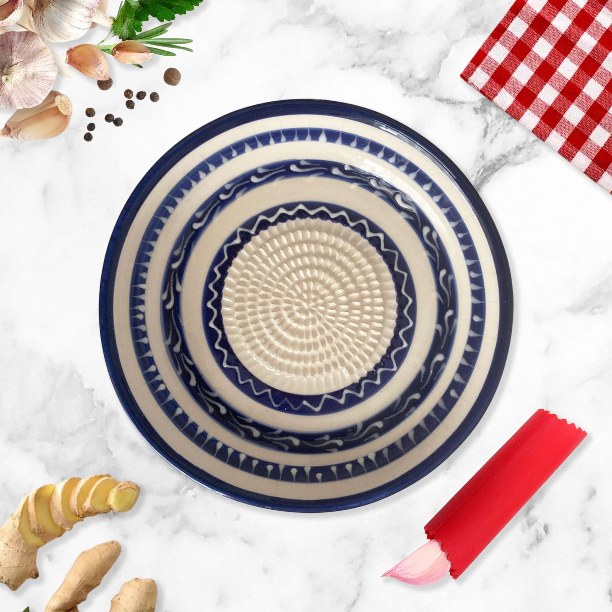 Decorative ceramic garlic grater bowl with blue and beige patterns on a marble surface with kitchen items.