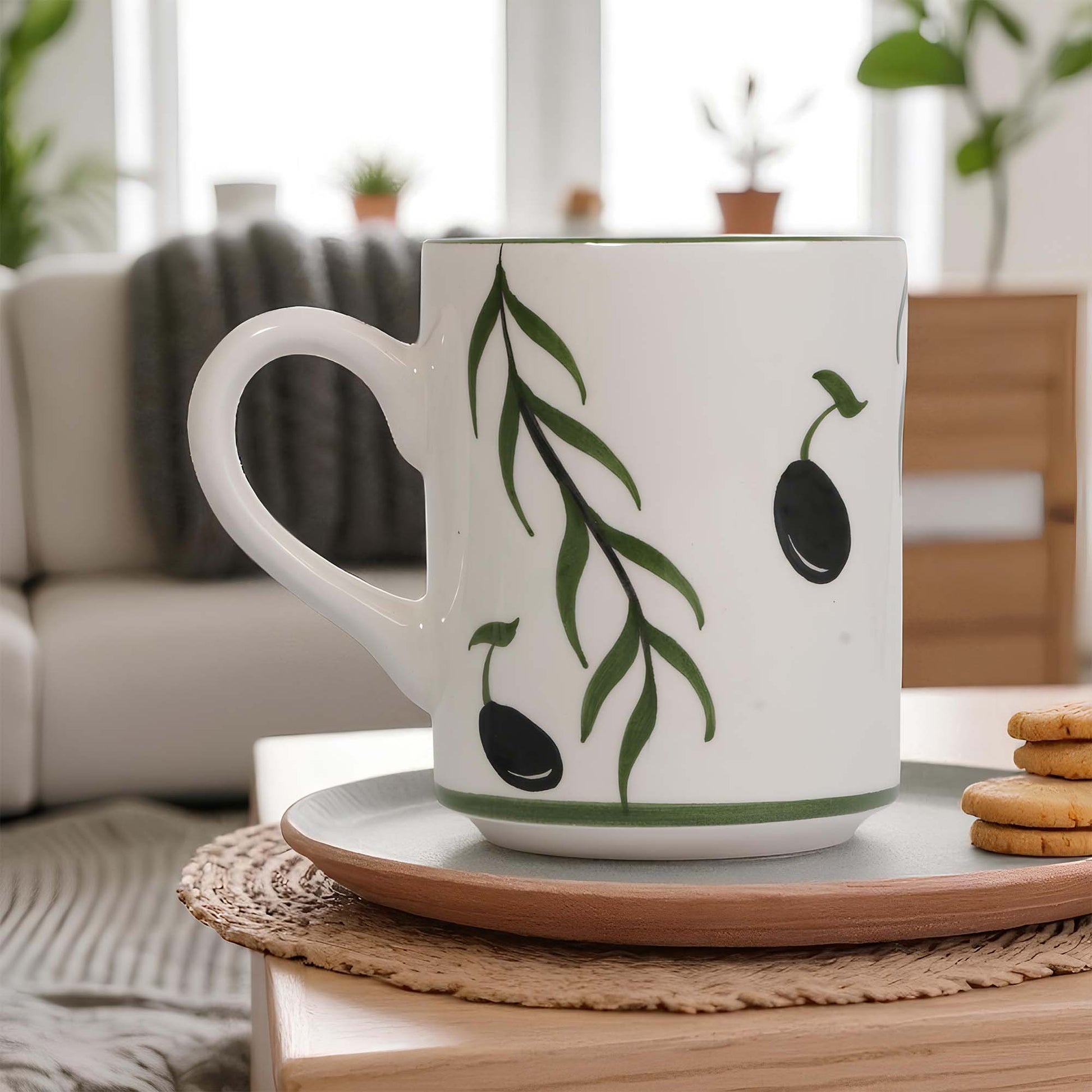 White coffee mug with green leaf design on a wooden table in a cozy living room.