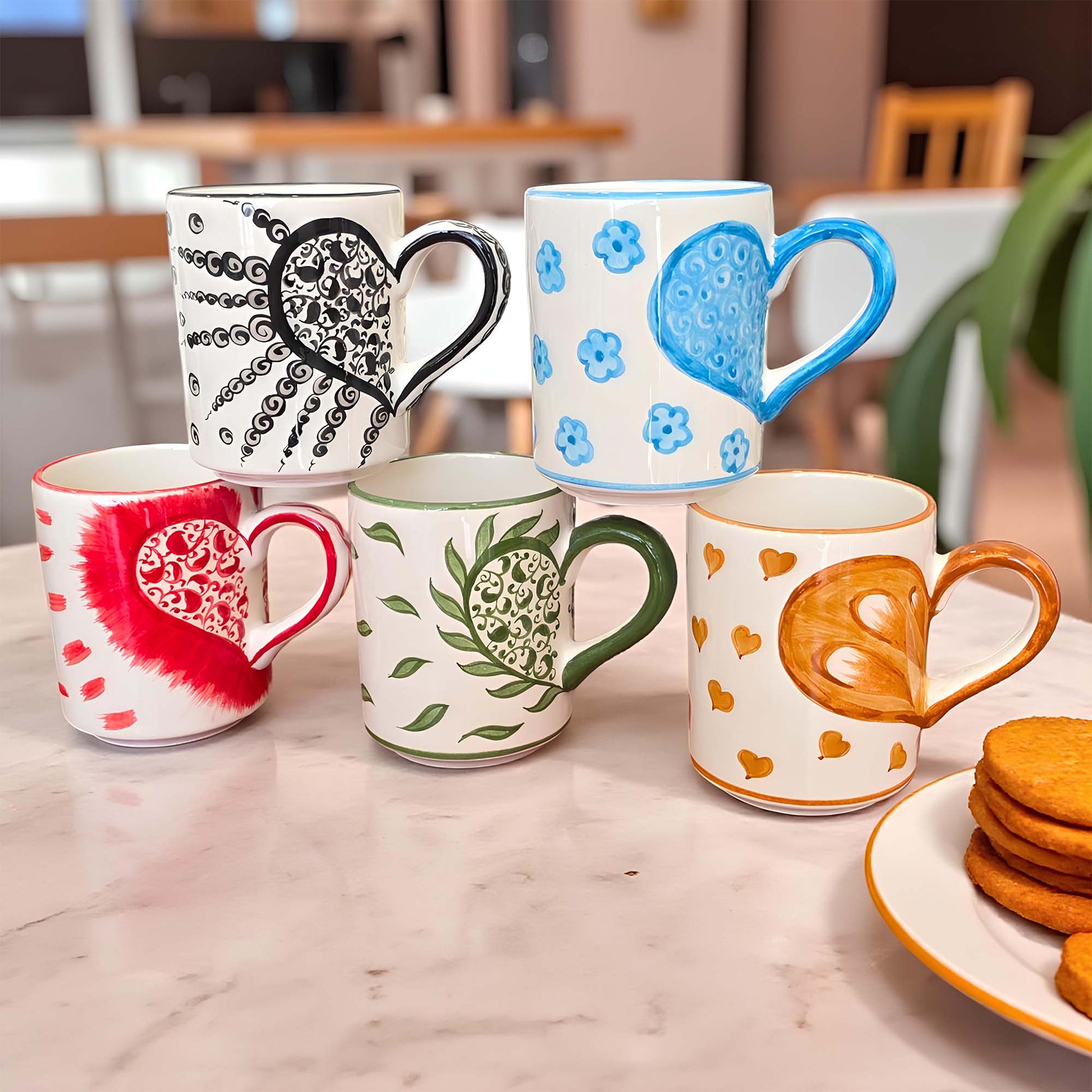 Set of colorful mugs with various designs on a marble surface.