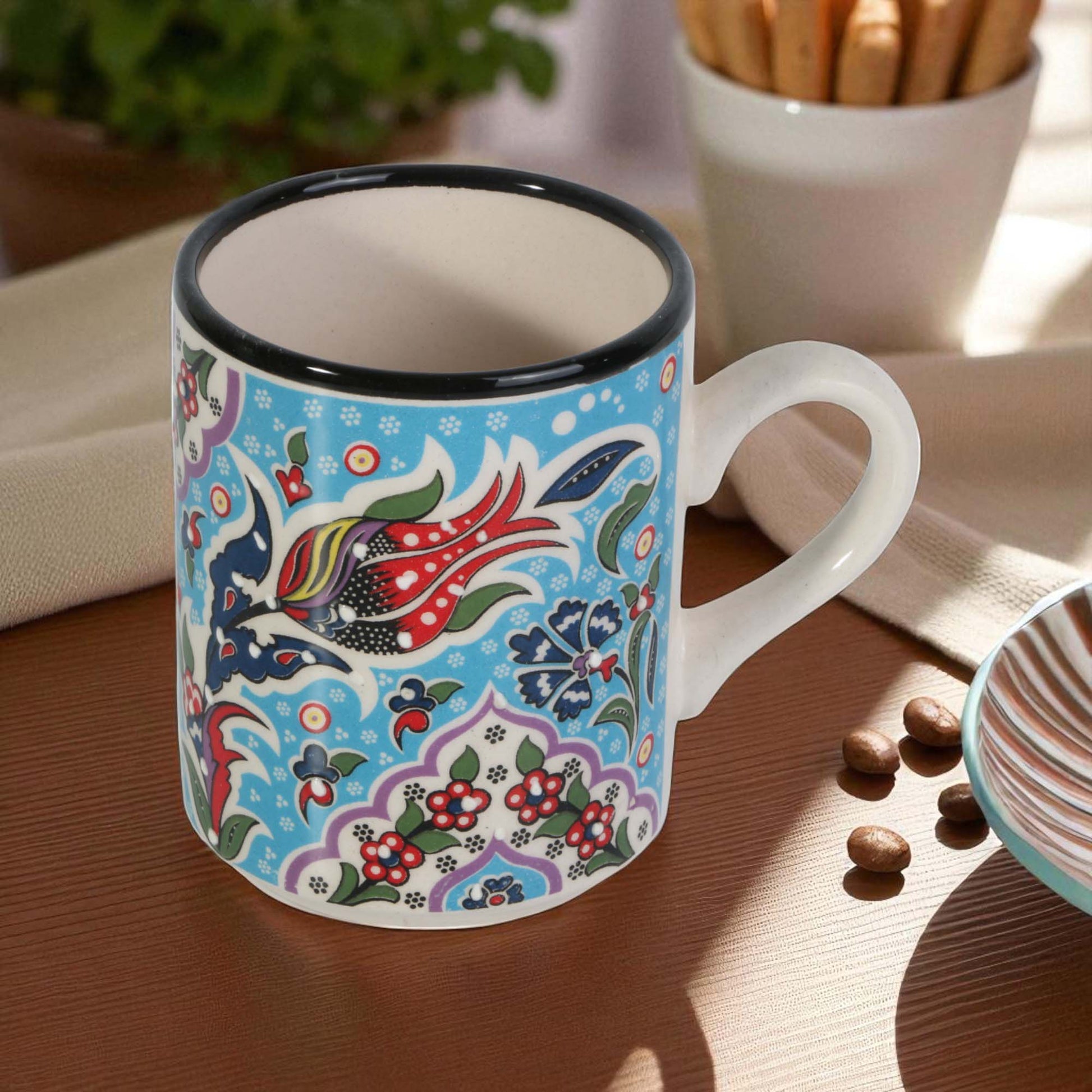 Colorful mug with floral and bird design on a wooden table.